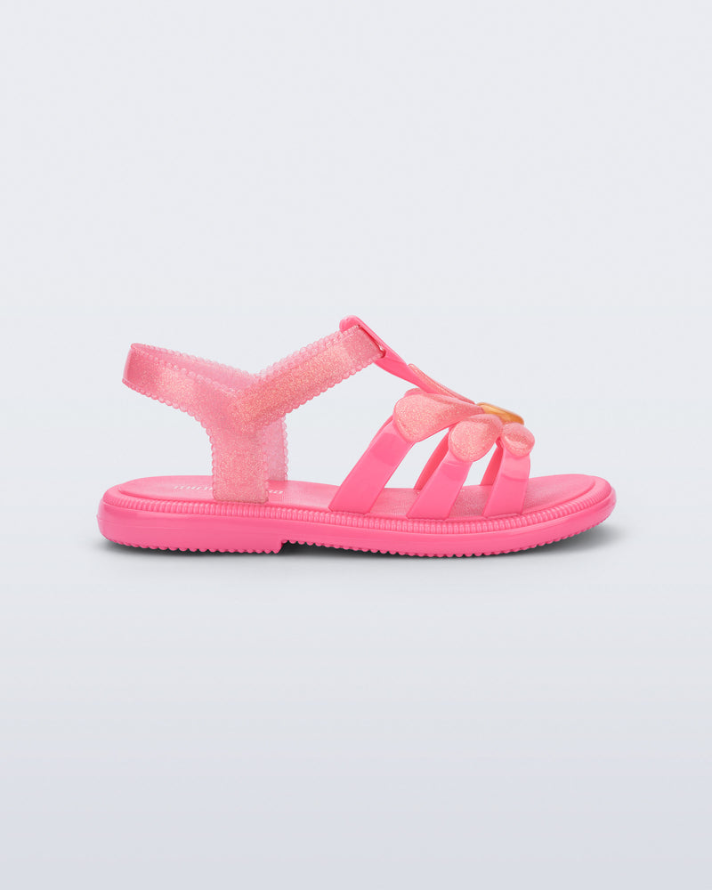 Side view of a glitter pink Hip Bloomy baby sandal with pink daisy on top