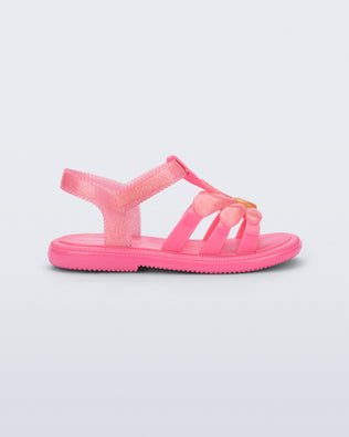 Side view of a glitter pink Hip Bloomy baby sandal with pink daisy on top