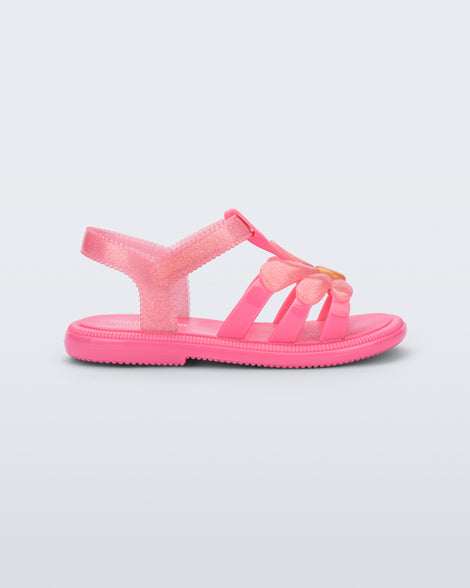 Side view of a glitter pink Hip Bloomy baby sandal with pink daisy on top