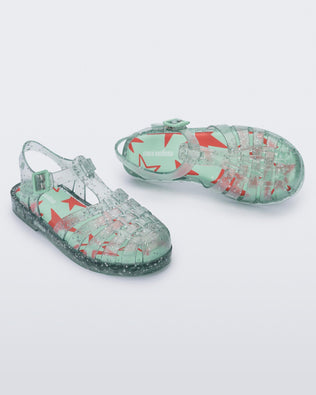 Top and angled view of a pair of clear green star glitter Possession kids fisherman sandals
