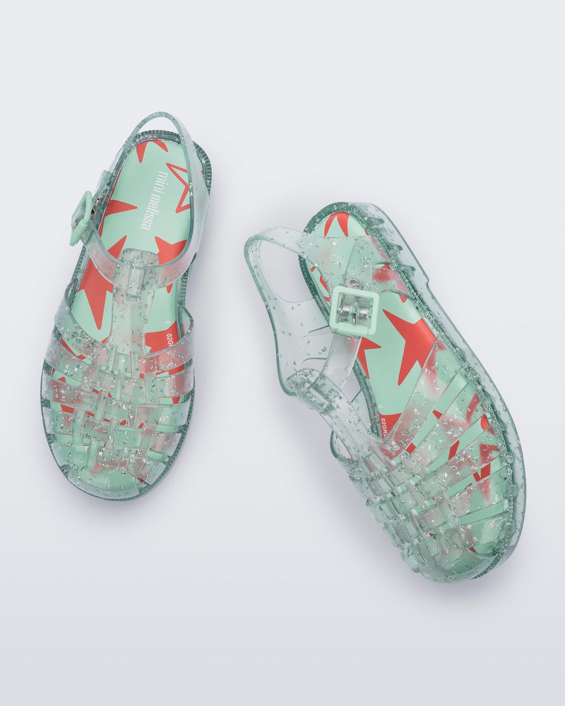Top angled view of a pair of clear green star glitter Possession kids fisherman sandals