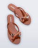 Top angled view of a pair of brown Harmonic Eclipse flip flops with bow. 