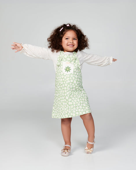 Child model in a white and green dress wearing a pair of metallic beige Ultregirl Princess baby ballerina flats