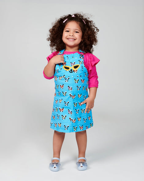 Child model in a blue dress wearing a pair of blue Ultragirl Princess baby ballerina flats.