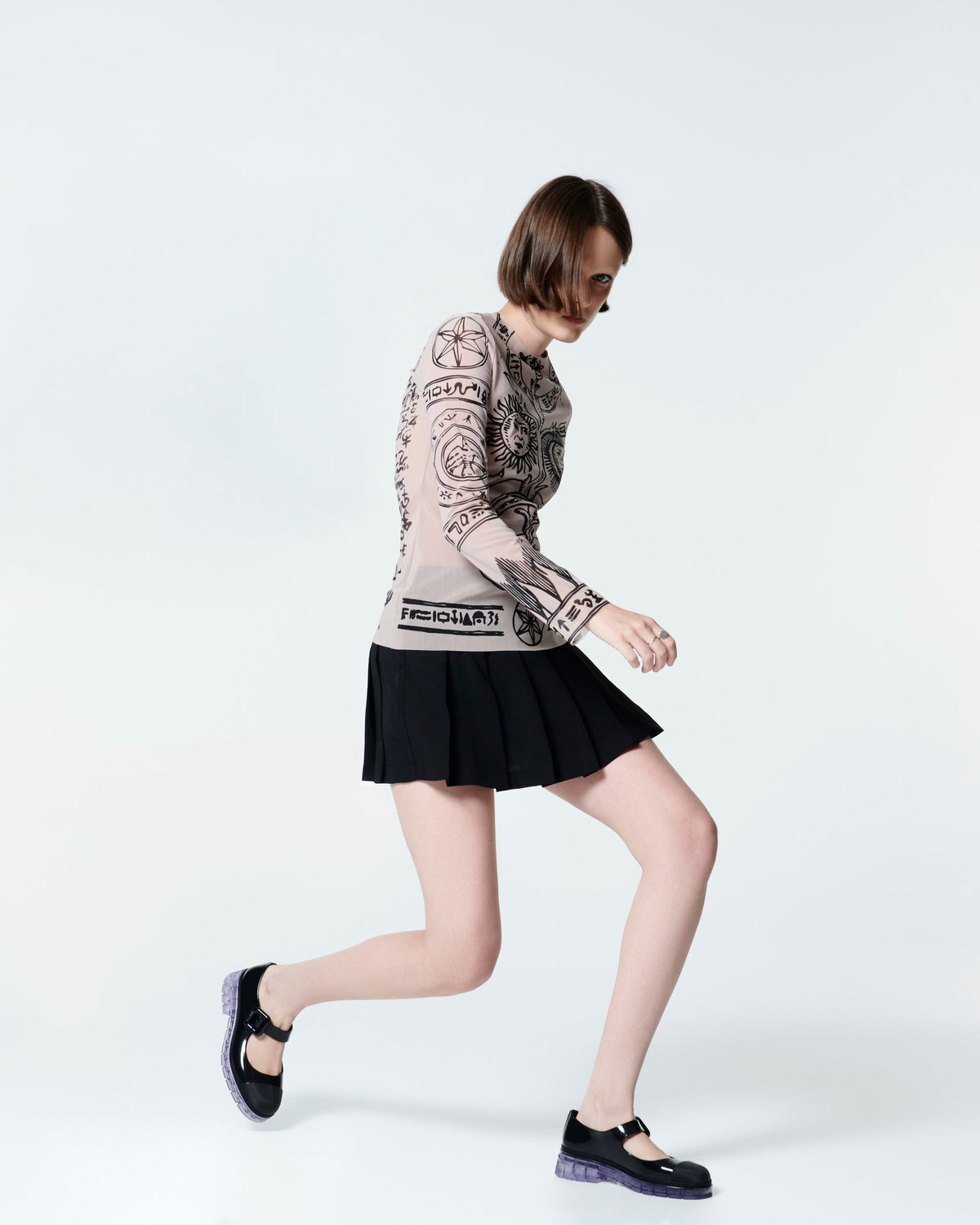 Model in a black skirt and sheer top wearing  a pair of black with clear sole June mary janes with matte toe cap