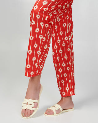 Model's legs in red pants wearing a pair of beige M Slides.