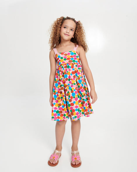 Child model in a multi colored dress wearing a pair of pink Hip Bloom kids sandals with pink flower