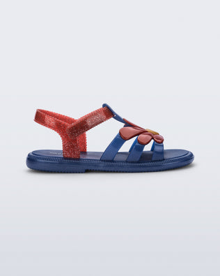 Side view of a glitter blue Hip Bloomy kids sandal with red daisy on top and red straps