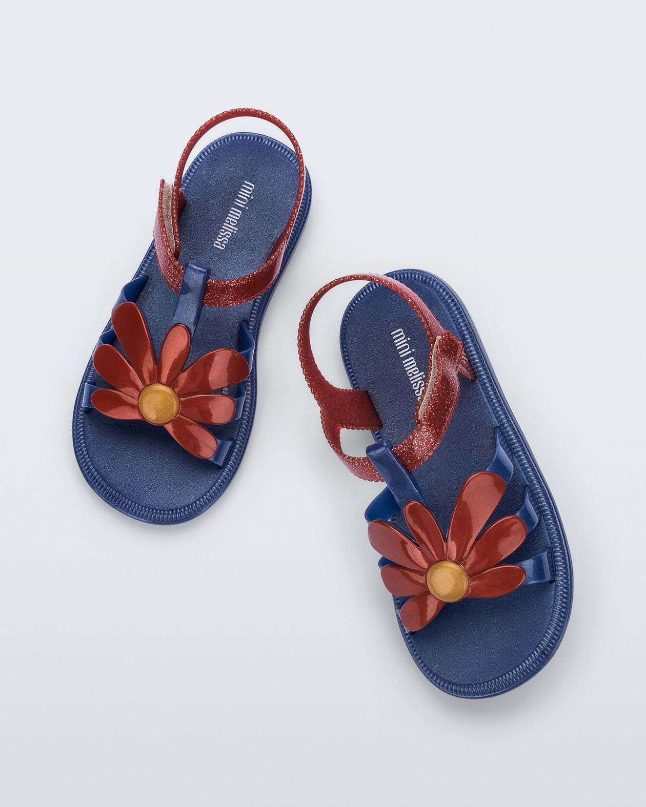 Top view of a pair of glitter blue Hip Bloomy kids sandals with red daisy on top and red straps