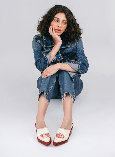 Model in blue jean cut off pants and jacket a pair of beige with red heel and accents Texas Mule heels