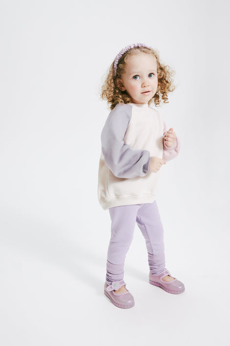 Child model in a purple pants and white shirt wearing a pair of pearly lilac Hip Ballerina flats