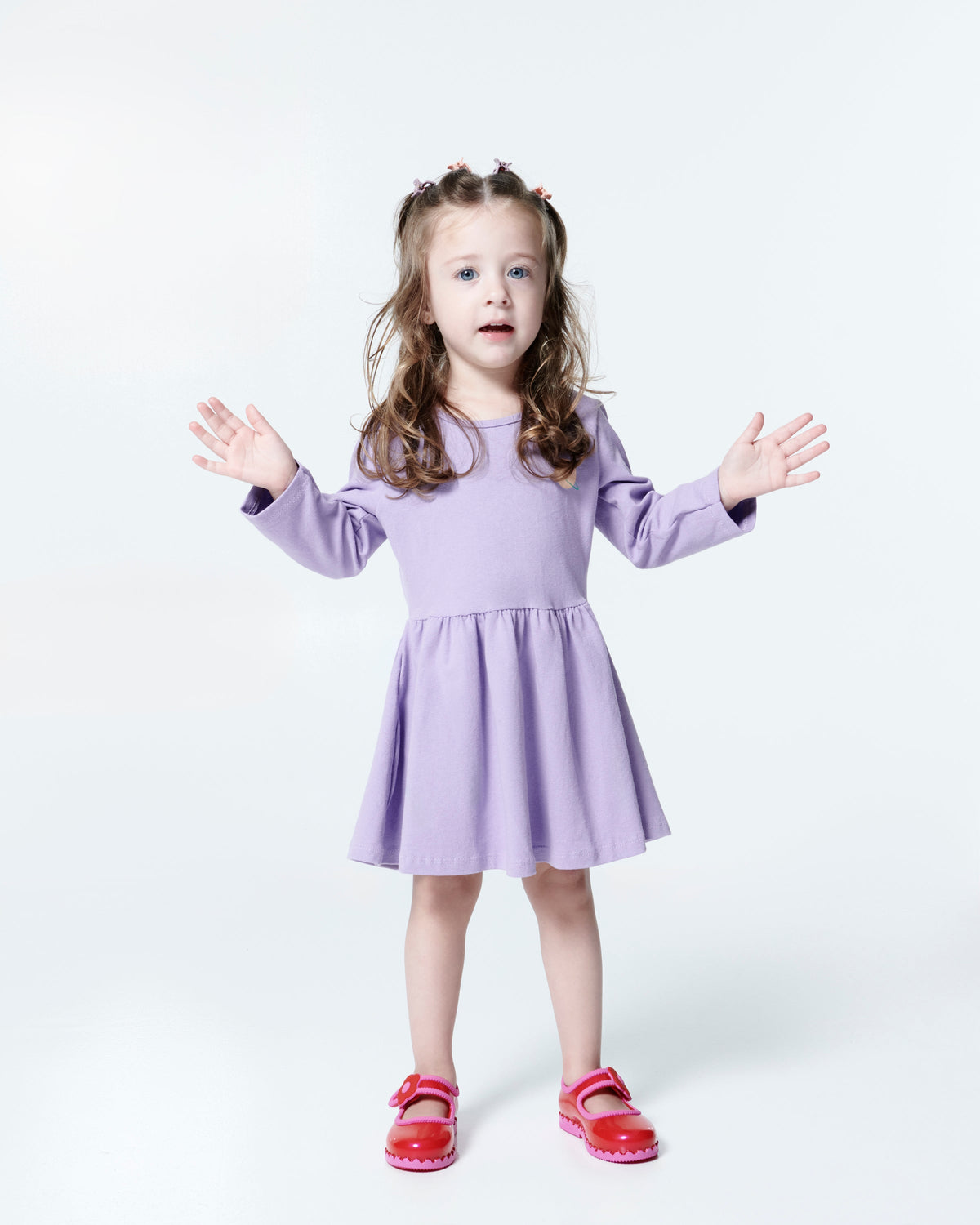 Child model in a purple dress wearing a pair of red/pink Hip Ballerina flats