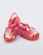 Angled view of a pair of pink/orange Possession Unicorn baby sandals with unicorn on front upper