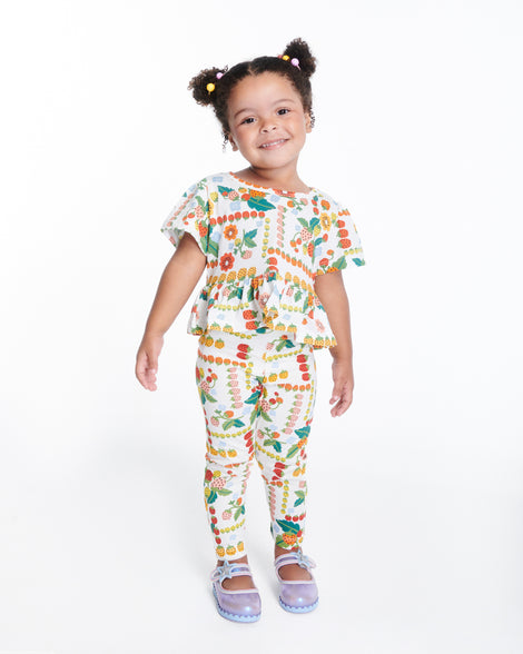 Child model in a multicolored outfit wearing a pair of pearly blue Hip Ballerina Star baby flats with star on upper strap