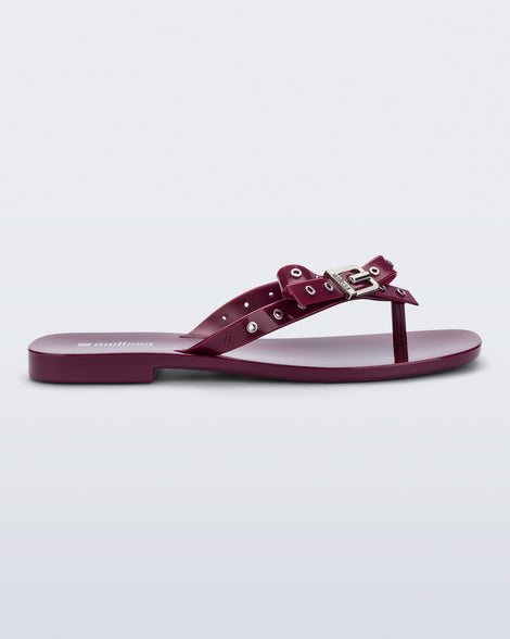 Side view of a red Harmonic Squared flip flop with bow on strap