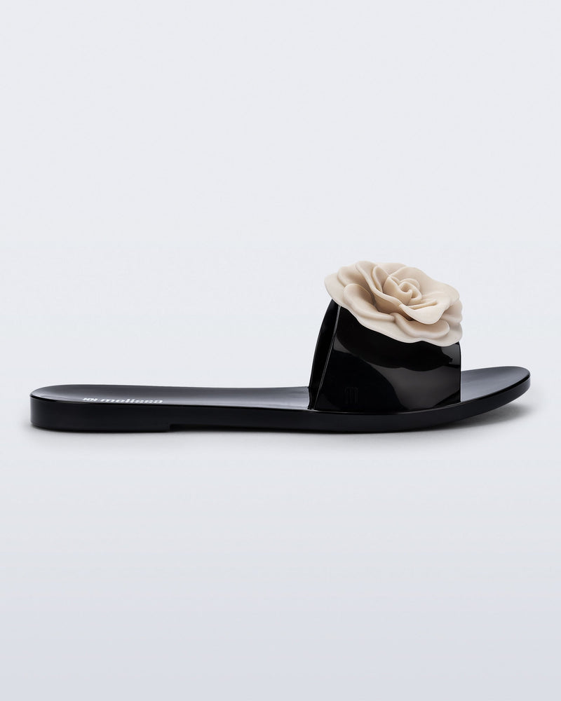 Side view of a black Babe Petals slide with beige flowers on top