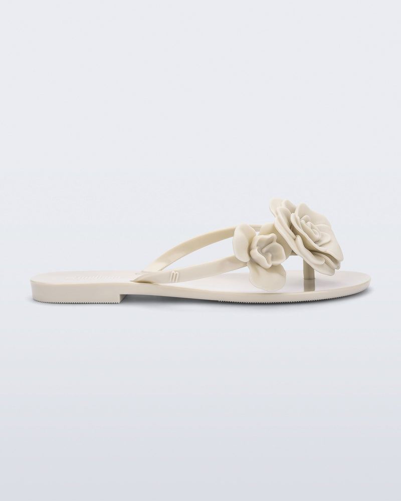 Side view of a beige Harmonic Petals flip Flop with beige flowers on top