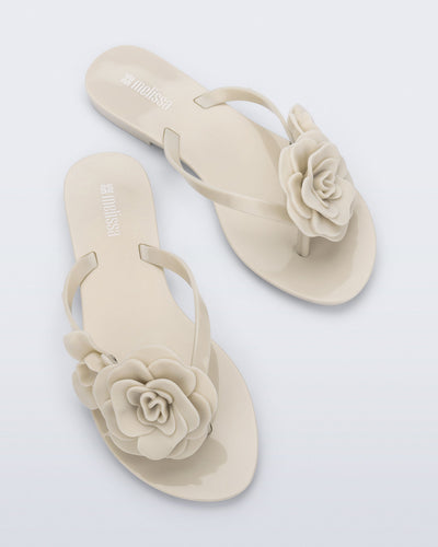Top view of a pair of beige Harmonic Petals flip Flop with beige flowers on top
