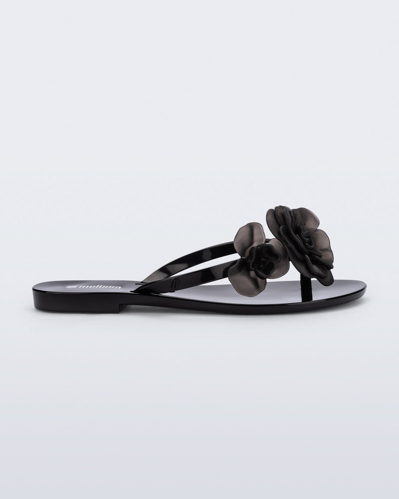 Side view of a black Harmonic Petals flip Flop with black flowers on top