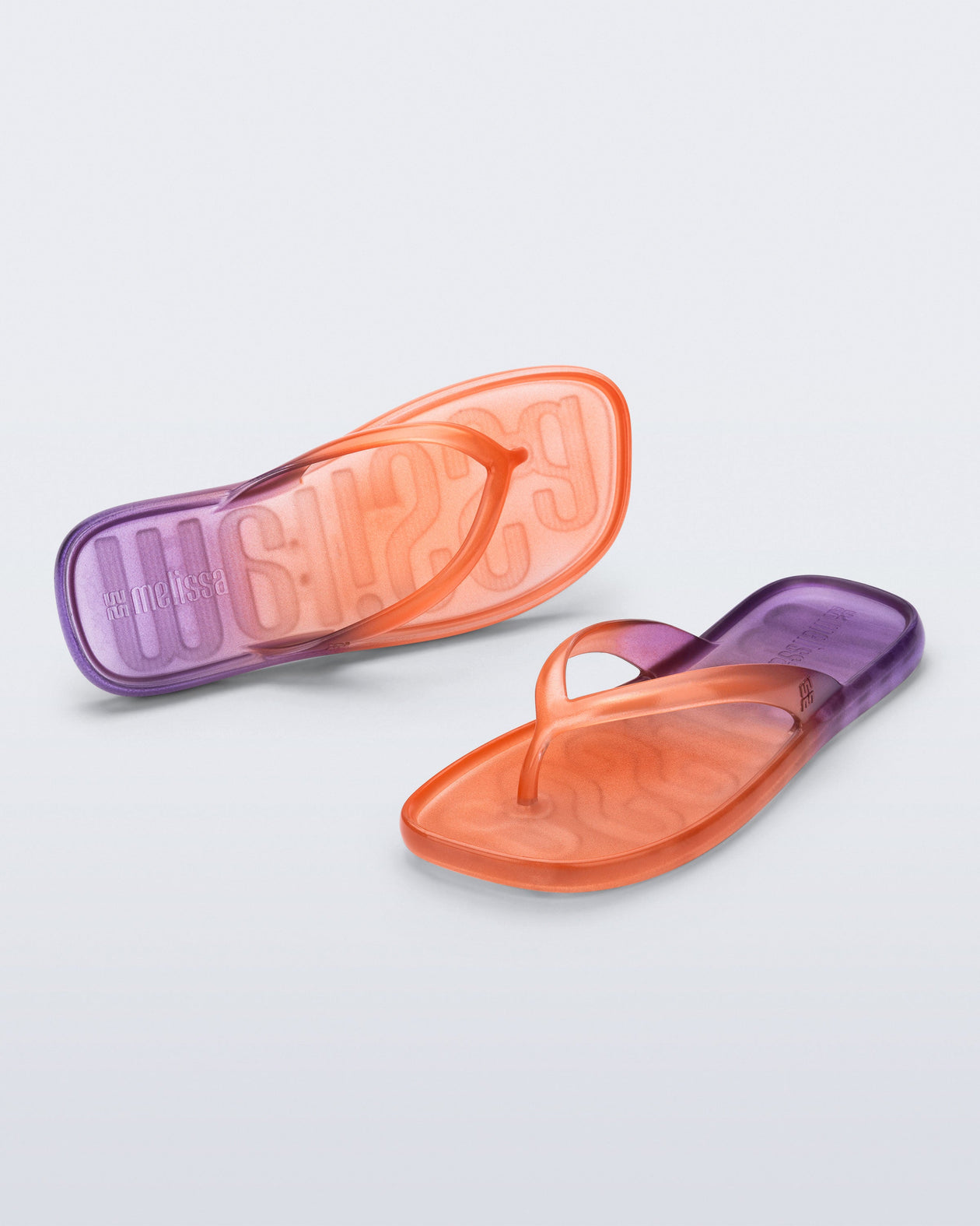 Top and angled view of a pair of orange/purple Beachwear flip flops