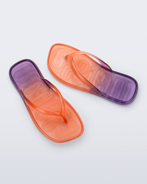 Top view of a pair of orange/purple Beachwear flip flops