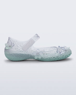 Side view of a clear Melissa + Susan Fang Luna Bloom flat with flower adornments and misty green sole