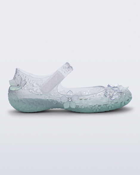 Side view of a clear Melissa + Susan Fang Luna Bloom flat with flower adornments and misty green sole