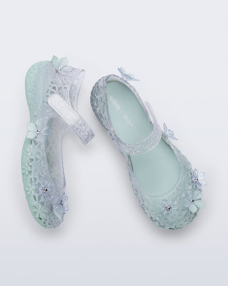 Top and side view of a pair of clear Melissa + Susan Fang Luna Bloom flats with flower adornments and misty green sole