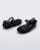 Back and side angled view of a pair of clear black Melissa + Susan Fang Luna Bloom flats with flower adornments 