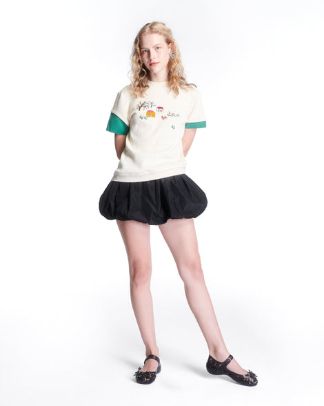 Model in a white shirt and black skirt wearing a pair of clear black Melissa + Susan Fang Luna Bloom flats with flower adornments 