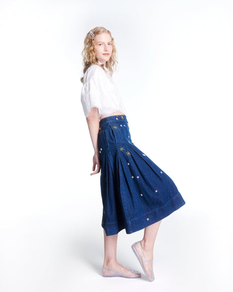 Model in a white top and blue long skirt wearing a pair of clear Melissa + Susan Fang Daphnis Ballerinas with t-top strap