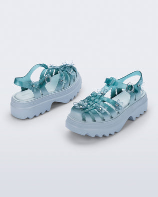 Back and side angled view of a pair of Clear misty blue/green Melissa + Susan Fang Possession Platform Sakura sandals with light blue soles