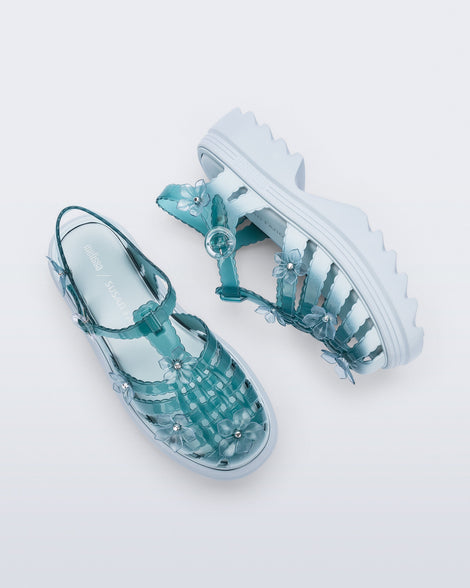 Top and side view of a pair of Clear misty blue/green Melissa + Susan Fang Possession Platform Sakura sandals with light blue soles