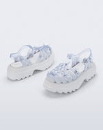 Back and side angled view of a pair of Clear Melissa + Susan Fang Possession Platform Sakura sandals with white soles
