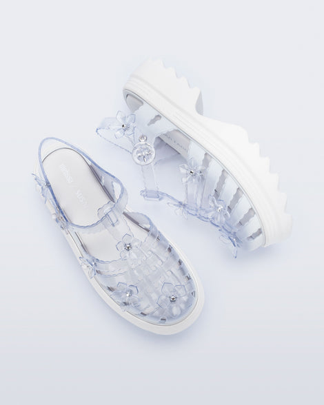 Top and side view of a pair of Clear Melissa + Susan Fang Possession Platform Sakura sandals with white soles