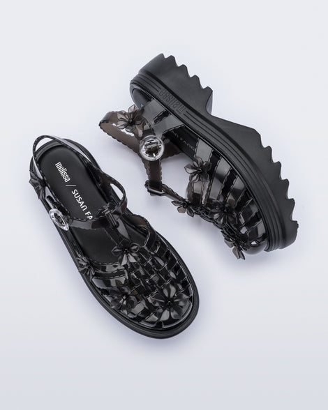 Top and side view of a pair of Clear black Melissa + Susan Fang Possession Platform Sakura sandals 