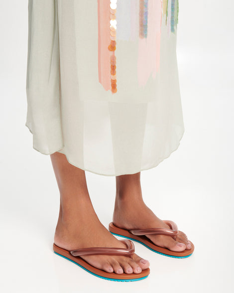 Model's legs wearing a pair of brown Flip Flop Airflow sandal with a clear brown strap and blue bottom