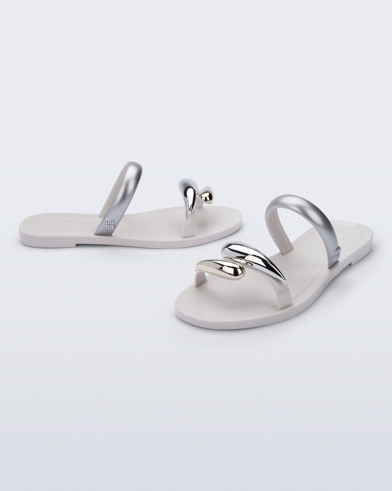 Side and angled view of a pair of white Eden sandals with metallic straps