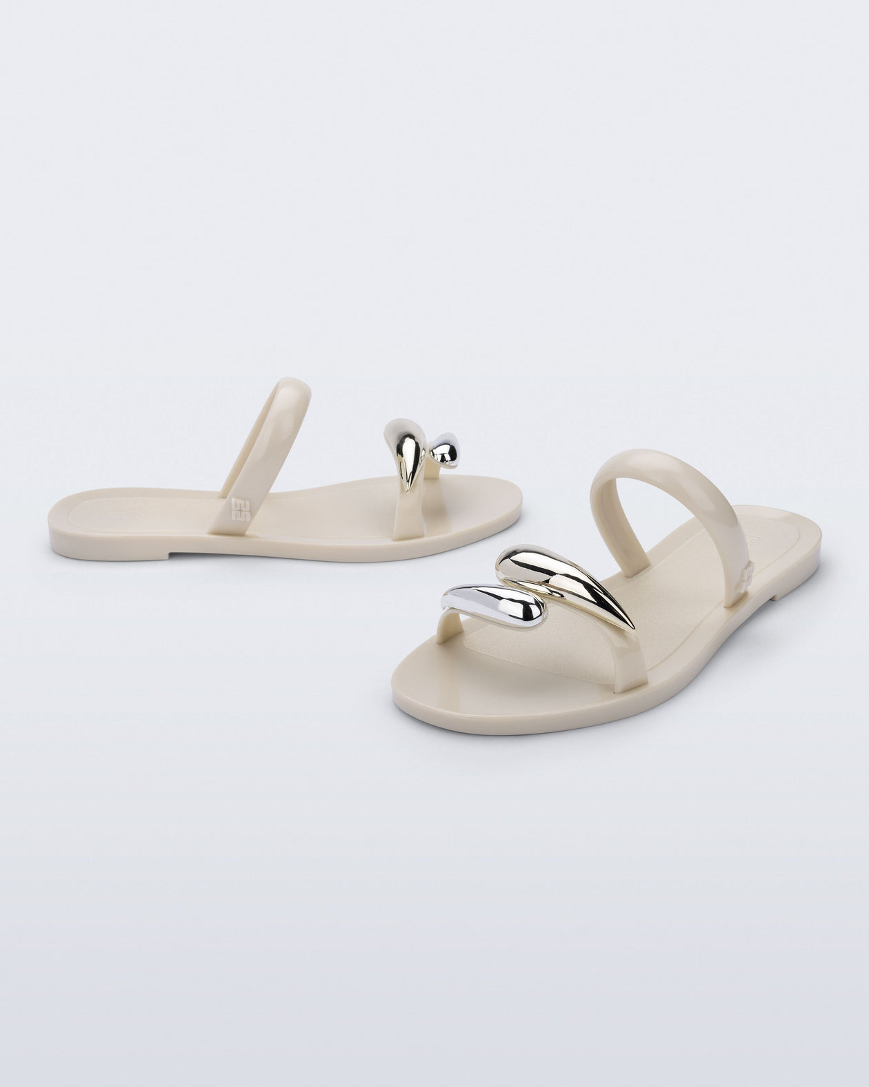 Side and angled view of a pair of beige Eden sandals with metallic straps