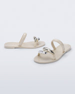 Side and angled view of a pair of beige Eden sandals with metallic straps
