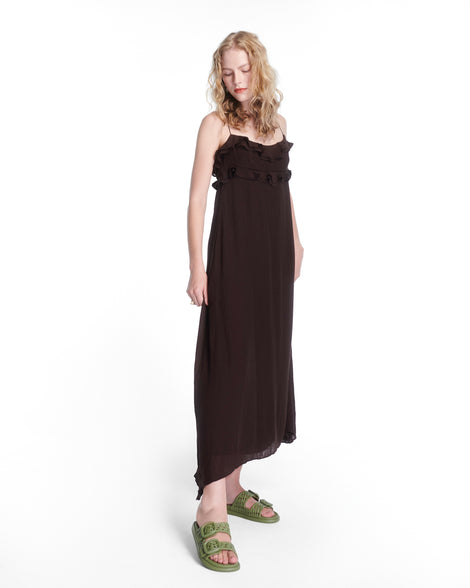 Model in a black dress wearing a pair of matte green Possession Slip sandals with two straps with buckles