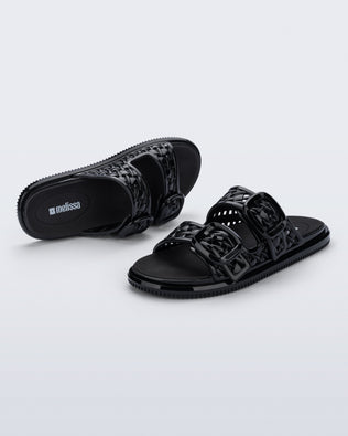 Top and side view of a pair of black Possession Slip sandals with two straps with buckles
