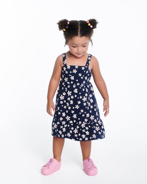 Child model in a black dress wearing a pair of pink Bloomy Sneaker with lilac laces and flower details on the sole