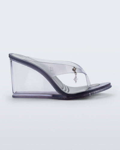 Side view of a clear grey Nabeela wedge flip flop with star charm on the strap