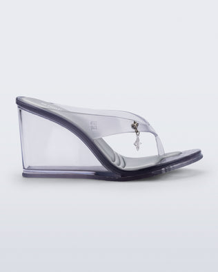 Side view of a clear grey Nabeela wedge flip flop with star charm on the strap