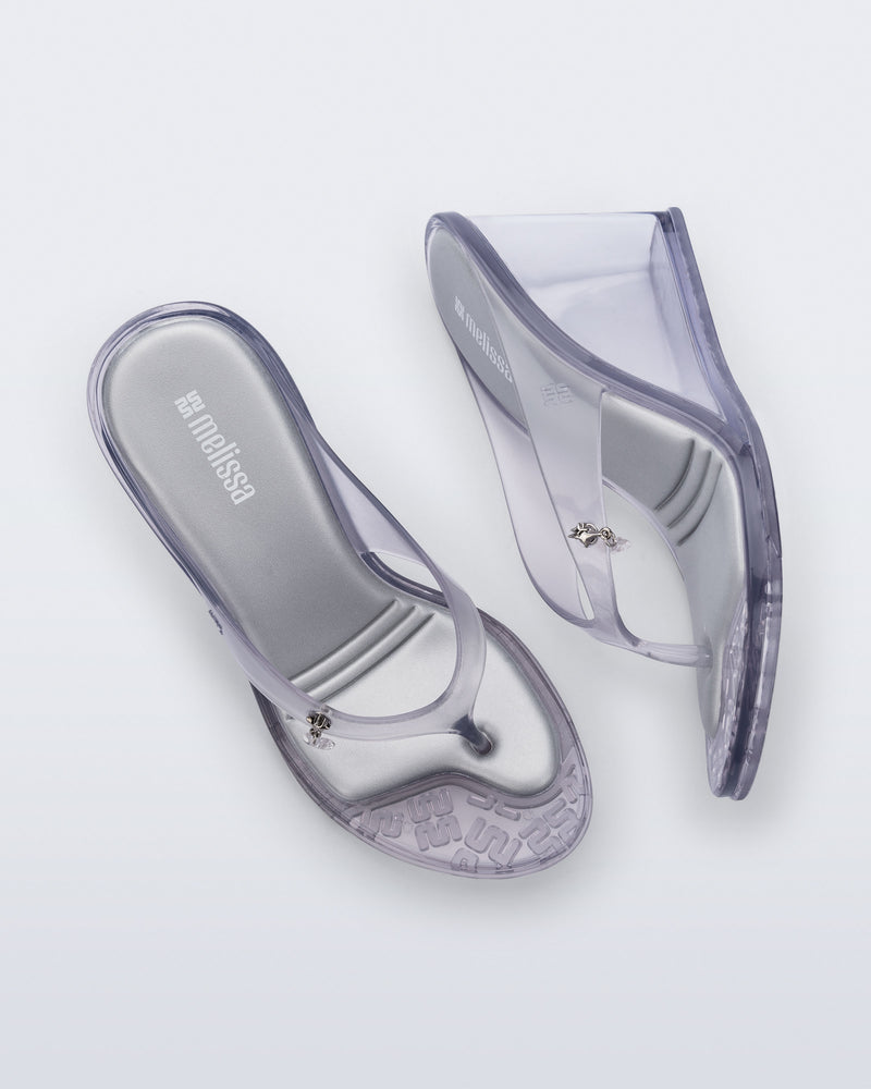 Top and side view of a pair of clear grey Nabeela wedge flip flops with star charm on strap
