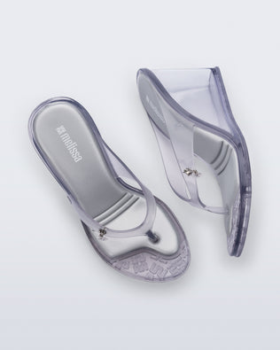 Top and side view of a pair of clear grey Nabeela wedge flip flops with star charm on strap