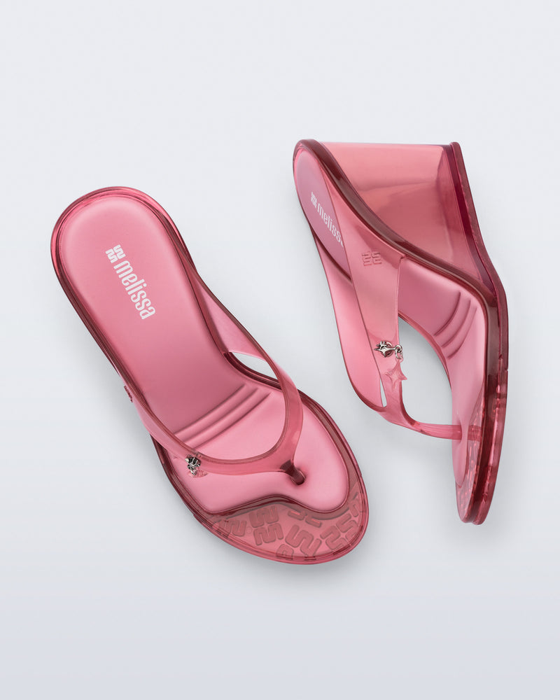 Top and side view of a pair of pink Nabeela wedge flip flops with star charm on strap