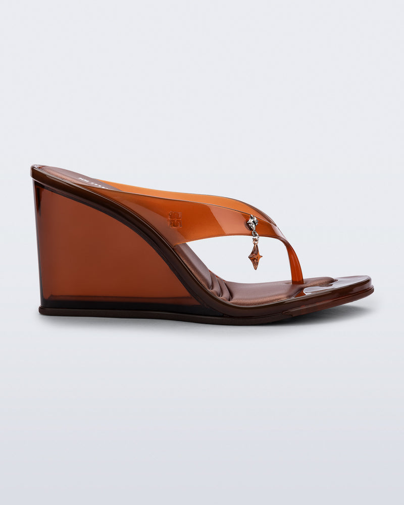 side view of a brown Nabeela wedge flip flop with star charm on strap