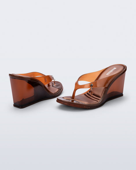 Back and angled view of a pair of brown Nabeela wedge flip flops with star charm on strap